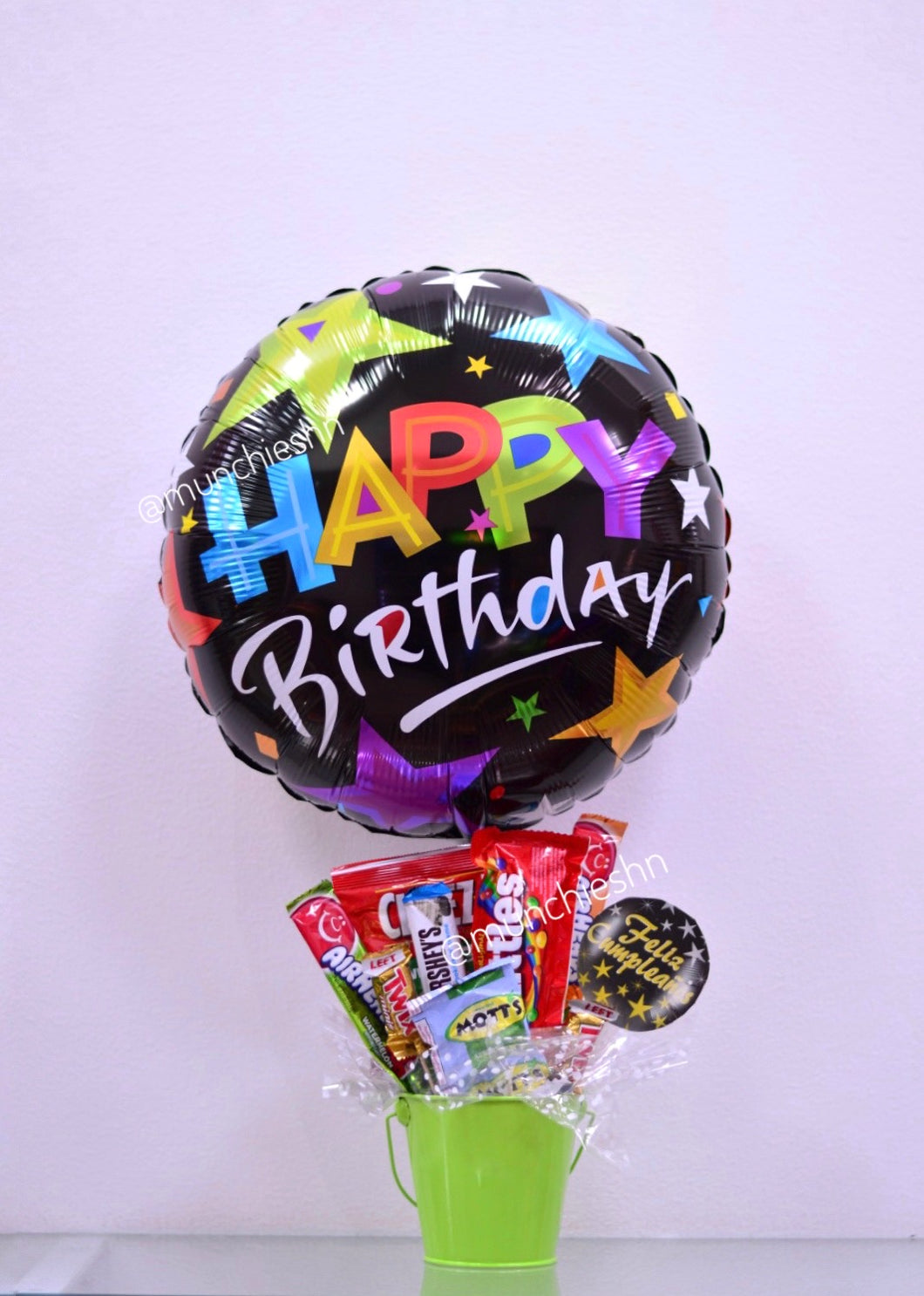 Arreglo de regalo con base de Cubeta metálica verde con dulces y chocolates americanos con globo grande negro de happy birthday,  ideal para expresar un feliz cumpleanos a alguien especial. Encuentralo en Tegucigalpa
