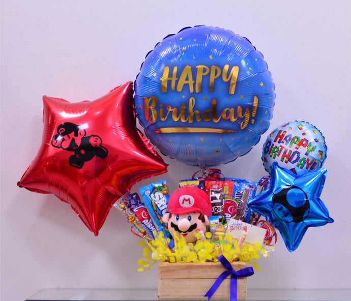 Arreglo de regalo con base caja de madera con snacks, chocolates, dulces americanos con globos medianos y globos grandes. Incluye peluche de Mario Bros. Perfecto para decir feliz cumpleanos a ese fanatico de Super Mario Bros.